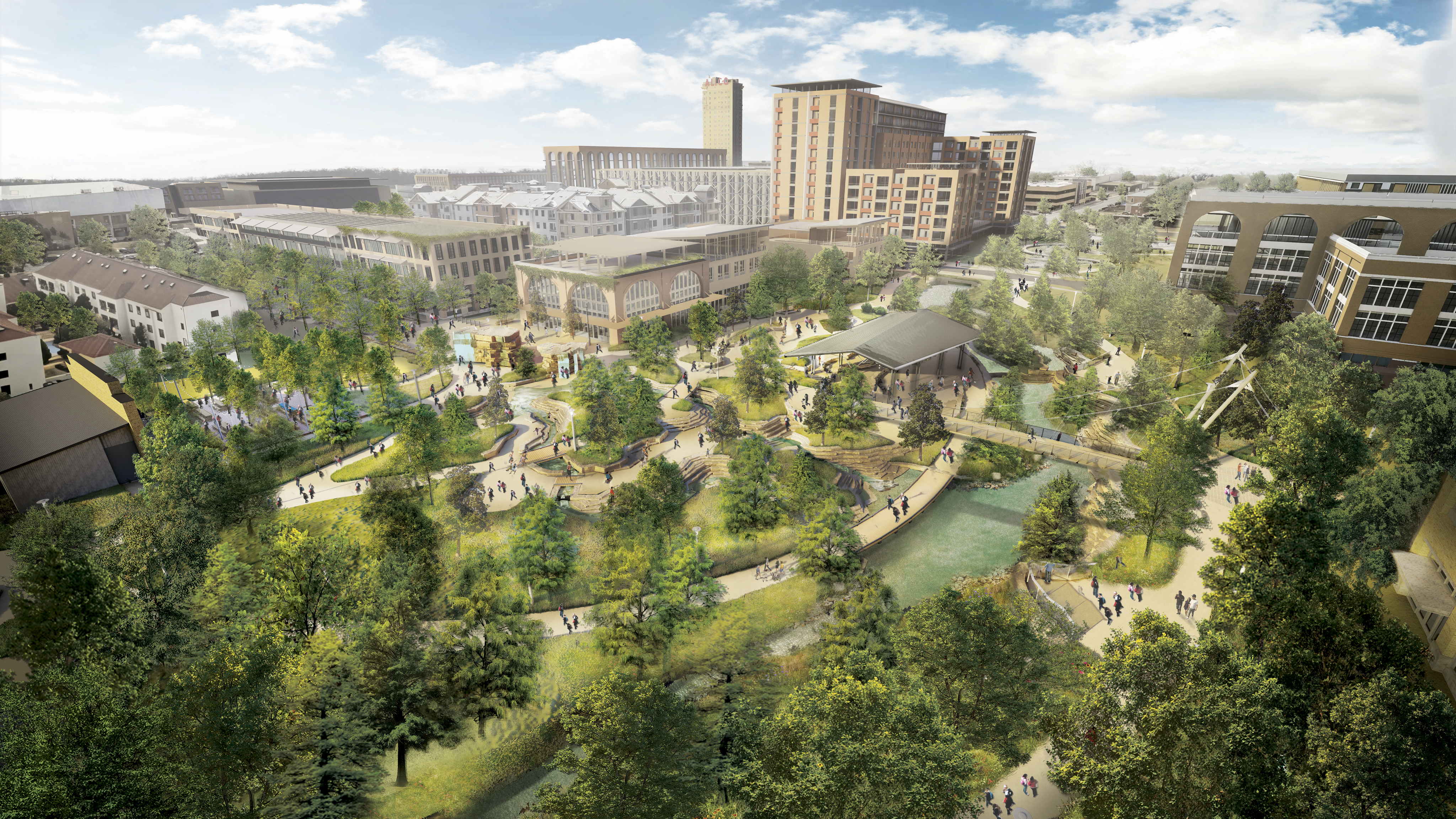 Aerial view of an urban park with trees, walking paths, a pond, and surrounding modern buildings on a sunny day.