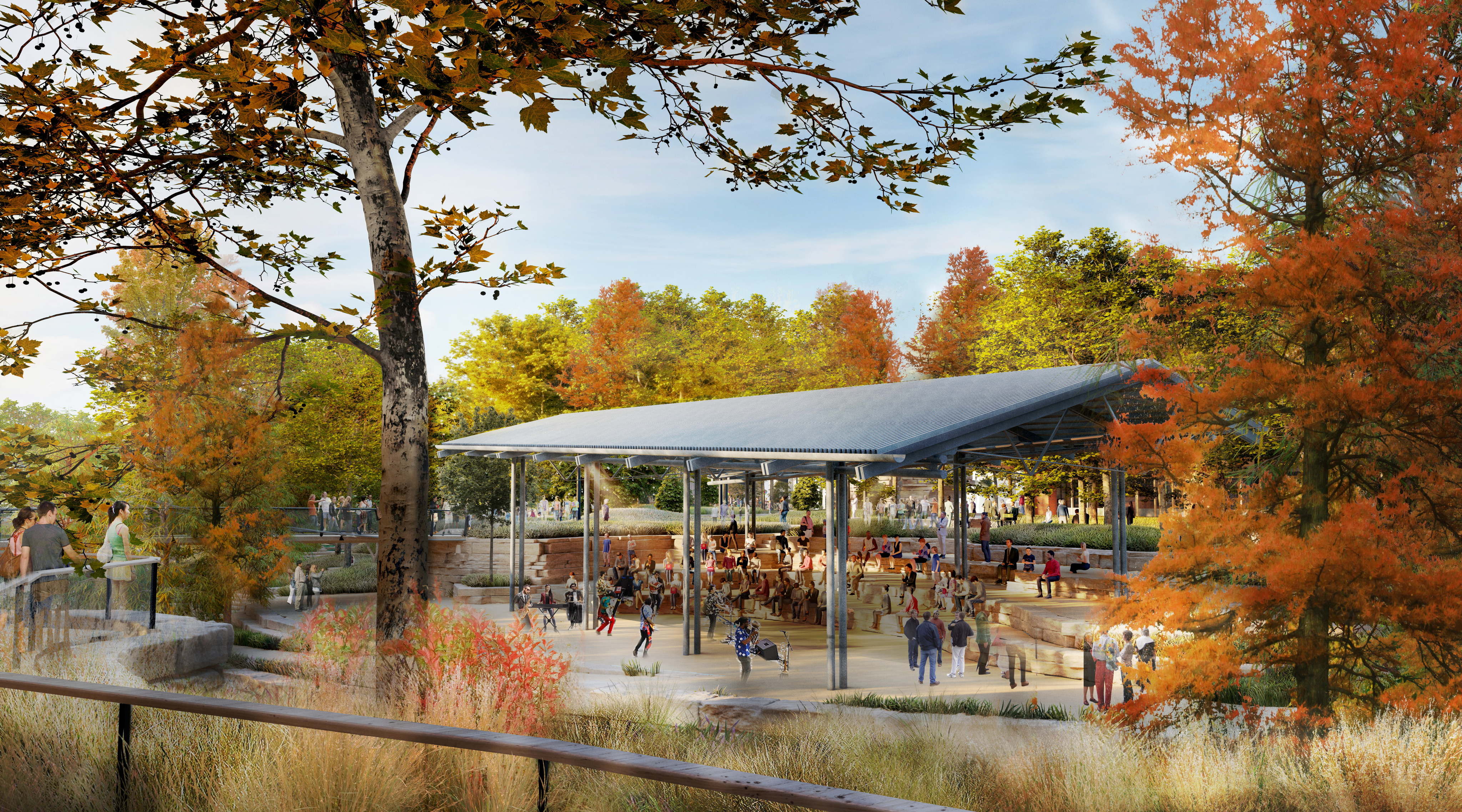People gather under a large open pavilion surrounded by autumn trees in a park, with some visitors walking nearby and natural landscaping in the foreground—creating a welcoming scene that reflects the community-focused vision of the Waco Master Plan for Downtown Waco.
